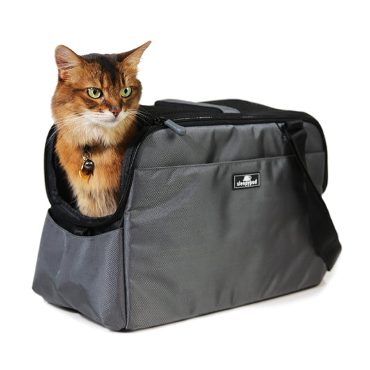 Cat peeking out from a gray pet carrier with a visible brand logo on a white background