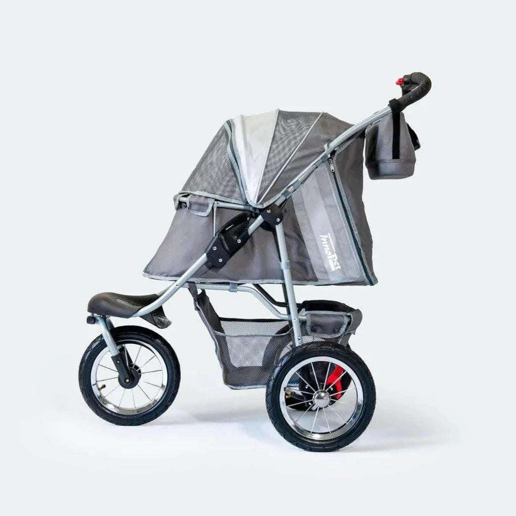 Innopet Comfort AIR ECO dog stroller in black and grey with mesh windows and air-filled tires on outdoor terrain