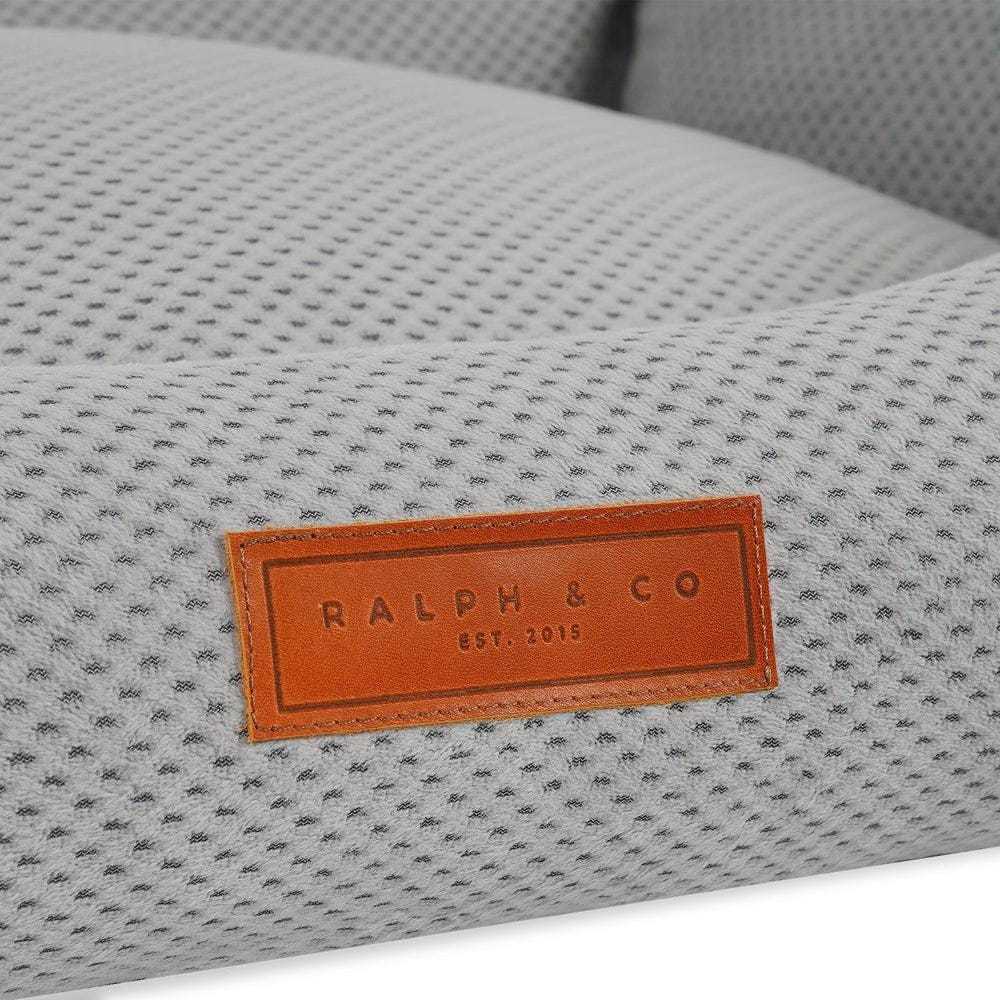Orthopedic memory foam dog bed with beige knitted upholstery and supportive bolster walls.